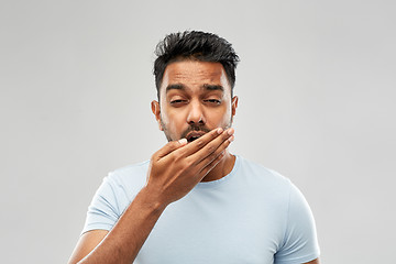 Image showing tired indian man yawning over grey background