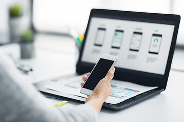 Image showing web designer with smartphone and laptop at office