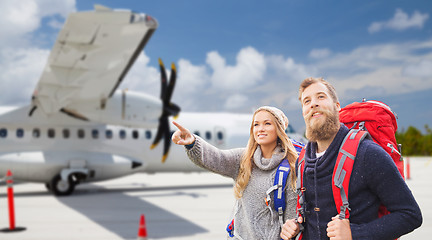Image showing couple of tourists with backpacks over plane