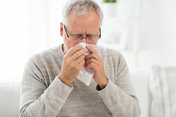 Image showing sick senior man with paper wipe blowing his nose