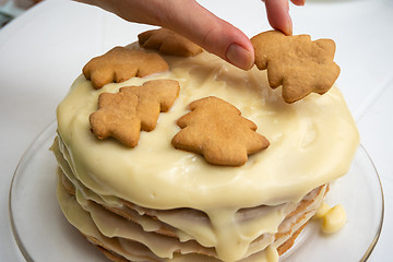 Image showing Homemade cake with condensed milk, a hand on top puts a Christmas tree cookie