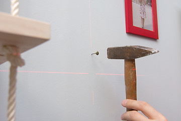 Image showing Hand hammering a nail into the wall, hanging frames with photos