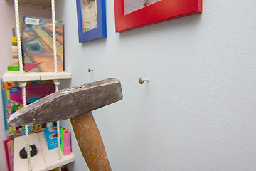 Image showing A hammer hammers a nail into the wall, hanging frames with photos