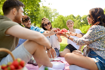 Image showing happy friends sharing watermelon at summer picnic