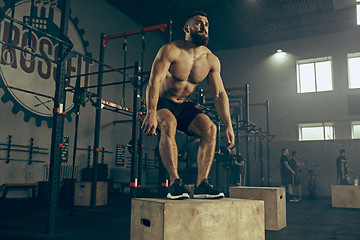 Image showing Man jumping during exercises in the fitness gym. CrossFit.