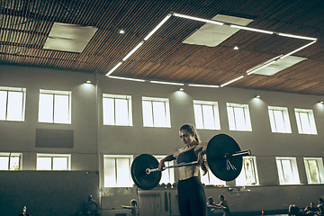 Image showing Fit young woman lifting barbells working out in a gym