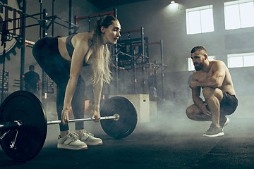 Image showing Fit young woman lifting barbells working out in a gym