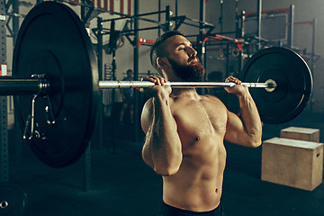 Image showing Fit young man lifting barbells working out in a gym