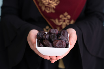 Image showing modern muslim woman holding a plate of dates in ramadan kareem