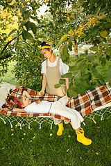 Image showing The happy young family during picking apples in a garden outdoors