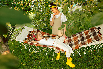 Image showing The happy young family during picking apples in a garden outdoors