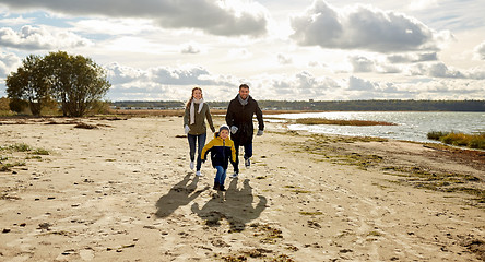 Image showing happy family running along autumn beach