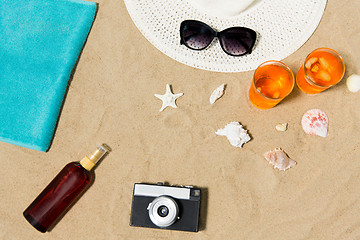 Image showing drinks, hat, camera and sunglasses on beach sand