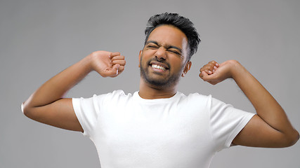 Image showing indian man stretching over grey background