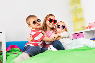 Image showing happy little kids in sunglasses hugging at home