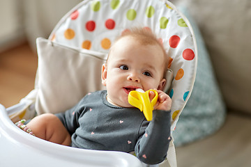 Image showing baby girl with teether toy in highchair at home