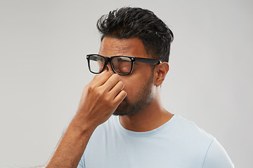 Image showing tired indian man in glasses rubbing nose bridge