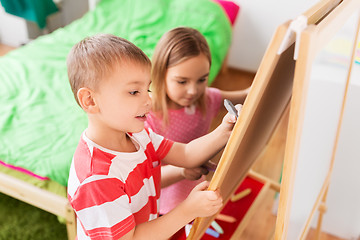 Image showing happy kids drawing on easel or flip board at home