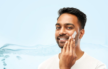 Image showing happy indian man applying cream to face