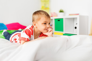 Image showing happy little boy lying on bed at home