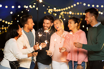 Image showing happy friends with sparklers at rooftop party