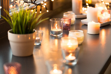 Image showing candles burning on window sill with garland lights