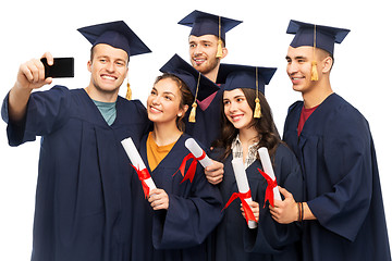 Image showing graduates with diplomas taking selfie by cellphone