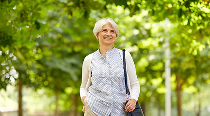 Image showing happy senior woman with handbag at summer park