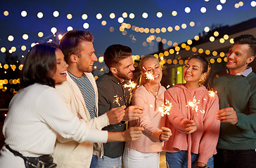 Image showing happy friends with sparklers at rooftop party