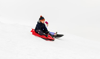 Image showing happy kids sliding on sleds down hill in winter