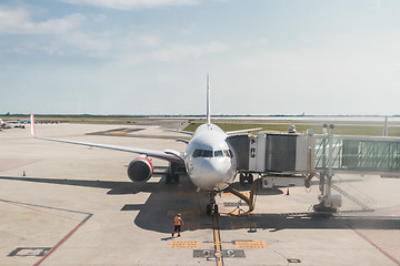 Image showing Modern commercial passenger airplane parked to airport terminal building