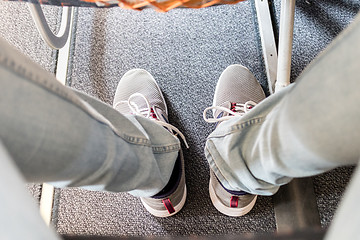 Image showing Male passenger with lack of leg space on long commercial airplane flight. Focus on casual sporty sneakers
