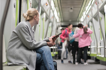 Image showing Beautiful blonde woman using smart phone while traveling by metro public transport.