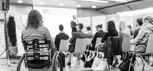 Image showing Rear view of unrecognizable woman on a wheelchair participating at business conference talk.