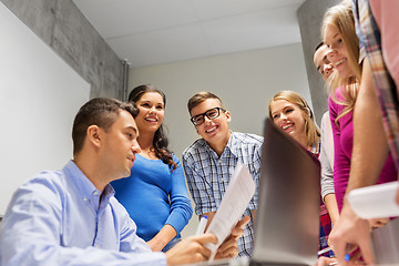 Image showing students and teacher with papers and laptop