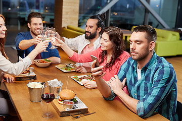 Image showing man messaging on smartphone at restaurant