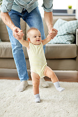 Image showing father helping baby daughter with walking at home