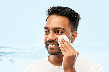 Image showing smiling indian man cleaning face with cotton pad