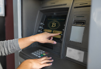 Image showing woman at atm machine with bitcoin icon on screen