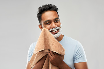 Image showing man removing shaving foam from face by towel