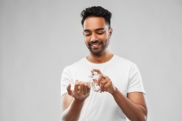 Image showing happy indian man with perfume over gray background