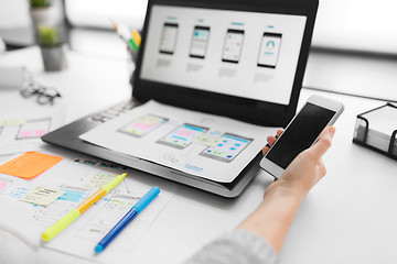 Image showing web designer with smartphone and laptop at office