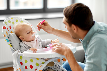 Image showing father feeding baby in highchair at home