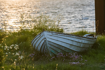 Image showing Old white rowing boat on land by sunset