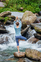 Image showing Woman in yoga asana Vrikshasana tree pose at waterfall outdoors