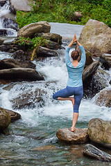 Image showing Woman in yoga asana Vrikshasana tree pose at waterfall outdoors