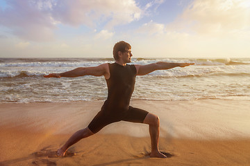 Image showing Man doing yoga asana Virabhadrasana 1 Warrior Pose on beach