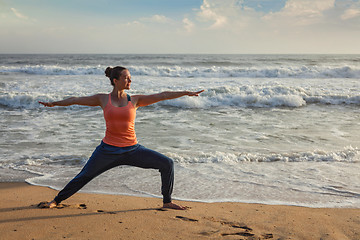 Image showing Woman doing yoga asana Virabhadrasana 1 Warrior Pose on beach on