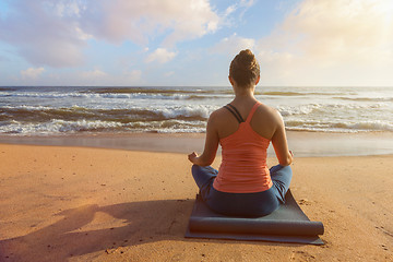 Image showing Woman doing yoga oudoors at beach - Padmasana lotus pose
