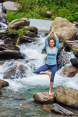 Image showing Woman in yoga asana Vrikshasana tree pose at waterfall outdoors